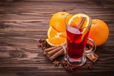 Cam mulled şarap, baharat ve ahşap arka plan üzerinde meyve ile