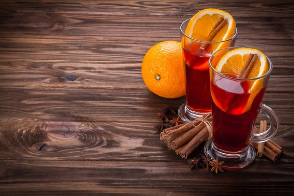 Copo com vinho quente, especiarias e frutas em fundo de madeira — Fotografia de Stock