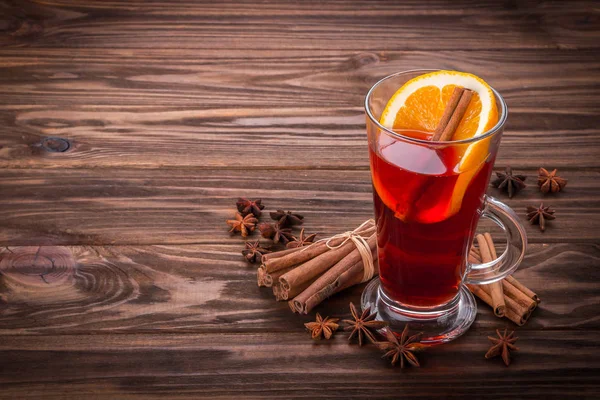 Verre avec vin chaud à la cannelle et anis sur fond en bois — Photo