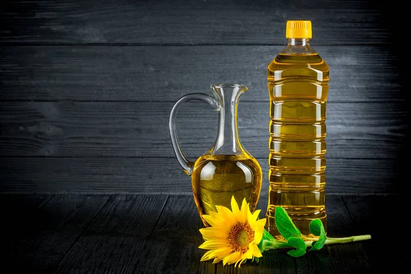 Sunflower oil with flowers on black rustic background — Stock Photo, Image