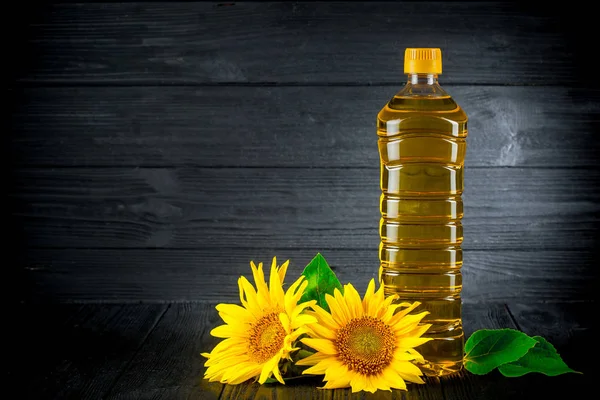 Olej słonecznikowy z kwiatami na czarnym tle rustykalnym — Zdjęcie stockowe