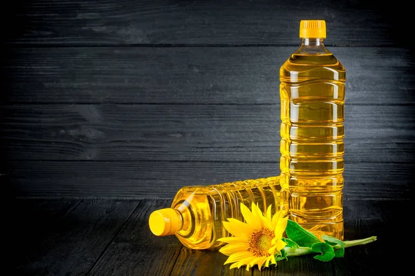 Sunflower oil with flowers on black rustic background — Stock Photo, Image