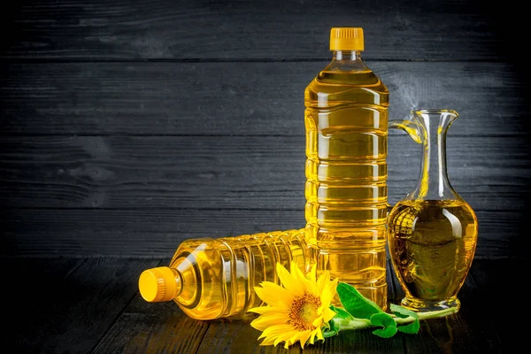 Sunflower oil with flowers on black rustic background — Stock Photo, Image