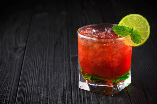 Red alcohol cocktail with mint and lime on black background — Stock Photo, Image