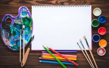 Boyalar, kalemler, sketchbook vintage ahşap zemin üzerine resim ve boş beyaz kağıt yaprağının için araçlar kümesi. Üstten görünüm.