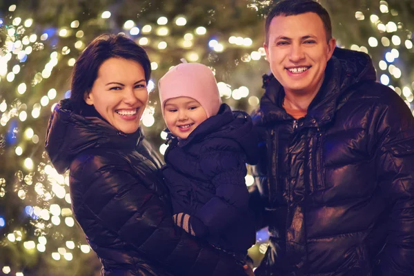 Ευτυχισμένη οικογένεια με μικρή κόρη πέρα από το υπόβαθρο των Χριστουγέννων — Φωτογραφία Αρχείου