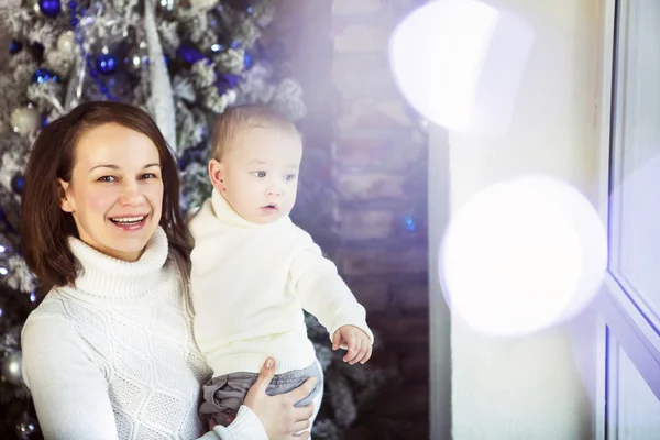 Madre con su bebé cerca del árbol de Navidad — Foto de Stock