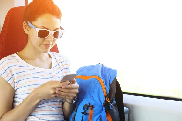 Mujer bonita viajando en tren sentado cerca de la ventana usando sm — Foto de Stock