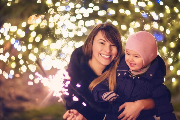 Mor och liten dotter med Bengaliska ljus över julen tillbaka — Stockfoto