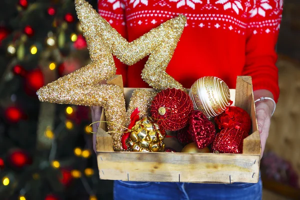 Uma mulher segura uma caixa com muitas decorações de Natal — Fotografia de Stock