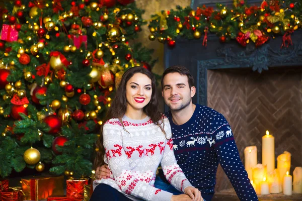 Young couple near fireplace celebrating Christmas