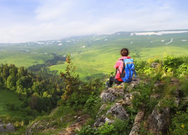 Uzun yürüyüşe çıkan kimse bir dağın tepesinde rahatlatıcı ve v zevk sırt çantası ile
