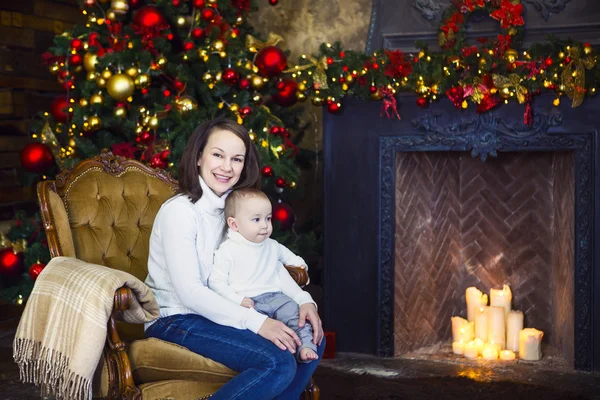 Moeder met haar babyjongen aanbrengen in de buurt van de kerstboom — Stockfoto