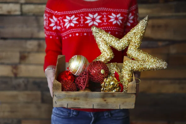 Uma mulher segura uma caixa com muitas decorações de Natal — Fotografia de Stock