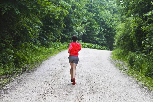 Jeune femme courant sur une route de campagne — Photo