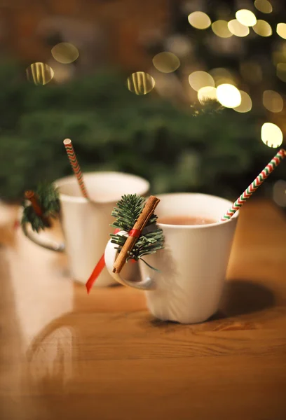 Hot chocolate with cinnamon sticks over Christmas background — Stock Photo, Image
