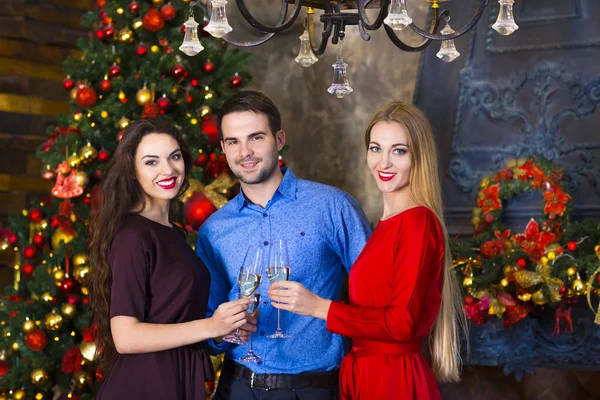 Jovens amigos perto da lareira celebrando o Natal — Fotografia de Stock