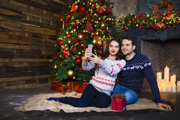 Mladý pár u krbu, slavit Vánoce — Stock fotografie