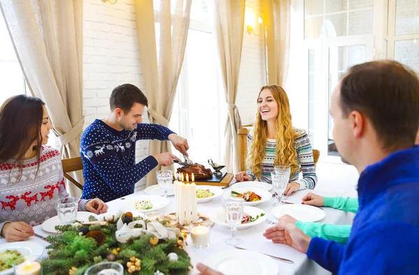 Vrienden zitten rond een tafel en genieten van de kerst diner tog — Stockfoto