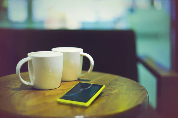 Coffee cups in coffee shop and mobile phone — Stock Photo, Image