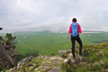Uzun yürüyüşe çıkan kimse bir dağın tepesinde rahatlatıcı ve v zevk sırt çantası ile