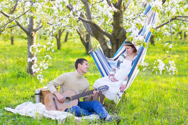 Zwanger koppel in een bloeiende tuin op de picknick — Stockfoto