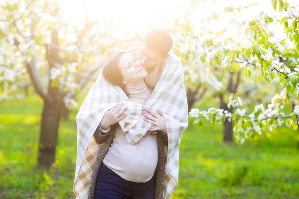 Happy pregnant couple in the blossom garden — Stock Photo, Image