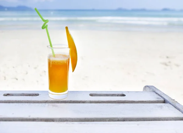 Glass of orange colour juice on the beach