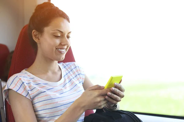 Mujer bonita viajando en tren sentado cerca de la ventana usando sm — Foto de Stock