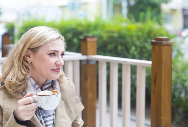 Close up happy adult blond woman with cup of coffee looking into — Stock Photo, Image