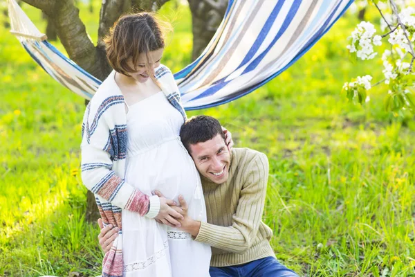 Happy pregnant couple in the blossom garden — Stock Photo, Image