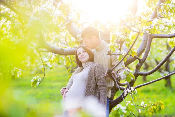 Lyckliga gravida par i blossom trädgården — Stockfoto