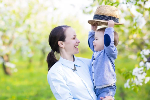 Malý chlapeček s matkou v rozkvetlé zahradě — Stock fotografie