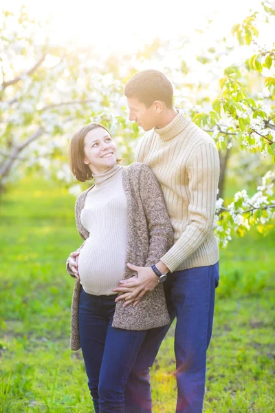 Happy pregnant couple in the blossom garden — Stock Photo, Image
