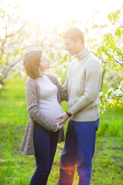 Gelukkige zwangere paar in de tuin van de bloesem — Stockfoto