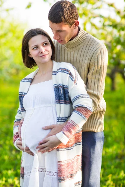 Happy pregnant couple in the blossom garden — Stock Photo, Image