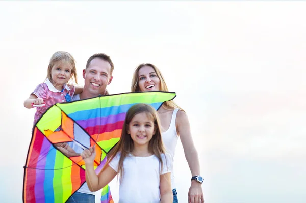 Gelukkig jonge lachende gezin met vliegen een vlieger op het strand — Stockfoto