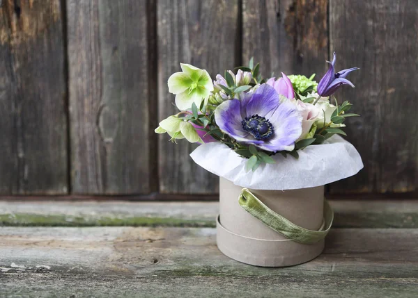 Bouquets of pink and violet flowers in the box on a woden backgr — Stock Photo, Image