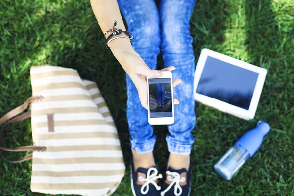 Telefone celular em uma mão de menina em uma grama verde — Fotografia de Stock