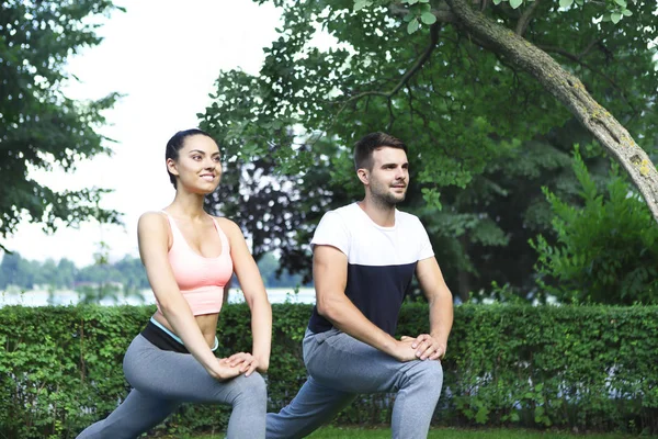Jovem casal exercitando e alongamento músculos antes esporte acti — Fotografia de Stock