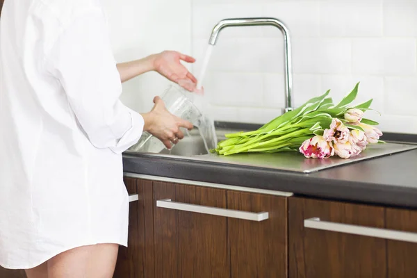 Young woman rinsing and cutting flowers and pouring water into t — Stock Photo, Image