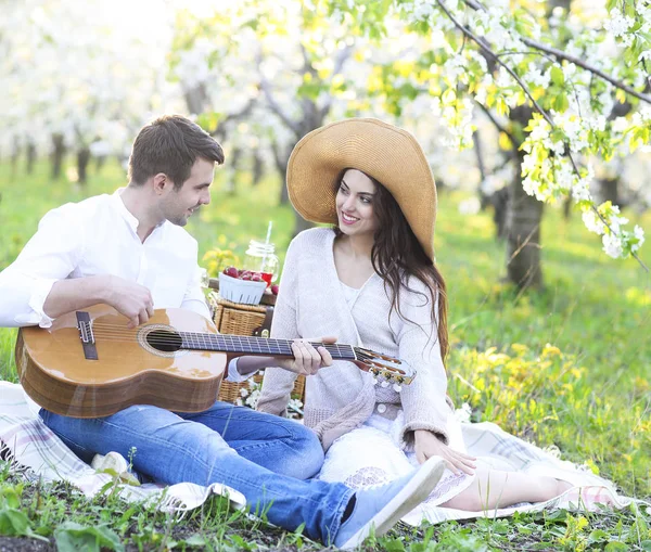 Mladý pár v lásce na pikniku v jarní kvetoucí zahrada — Stock fotografie