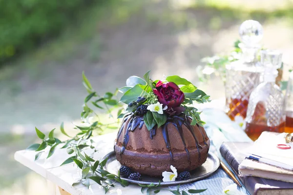 Cocolate cake decorated with flowers and three whiskey decanters