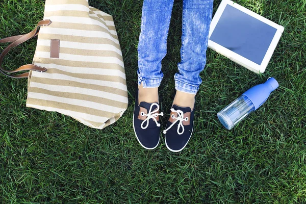 Los pies de una joven sobre un fondo una hierba verde con botella o — Foto de Stock