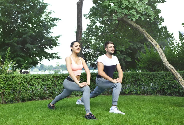 Young couple exercising and stretching muscles before sport acti — Stock Photo, Image