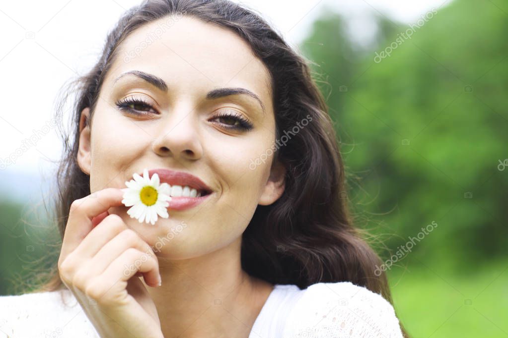 Happy pretty brunette woman in chamomile field