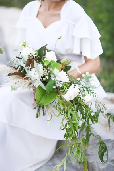 Giovane sposa in abito da sposa bianco tenendo bel bouquet — Foto Stock