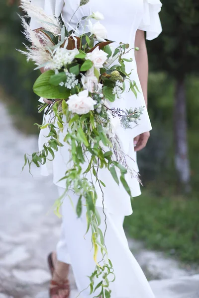 Giovane sposa in abito da sposa bianco tenendo bel bouquet — Foto Stock