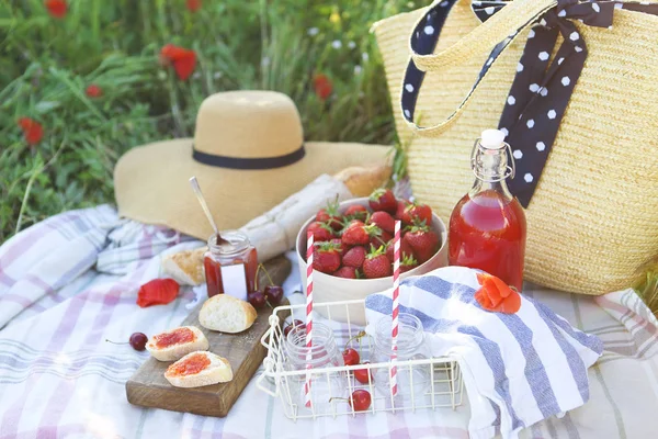 Basket, sandwiches, plaid and juice in a poppy field. — Stock Photo, Image