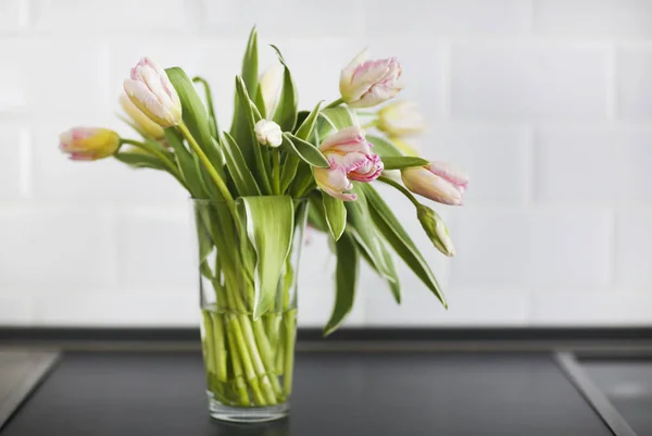 Růžové tulipány kytice ve skleněné váze na kuchyni — Stock fotografie